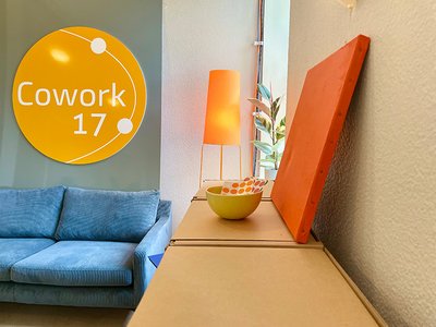 Räumlichkeit im Cowork17 mit dem Logo oberhalb eines blauen Sofas